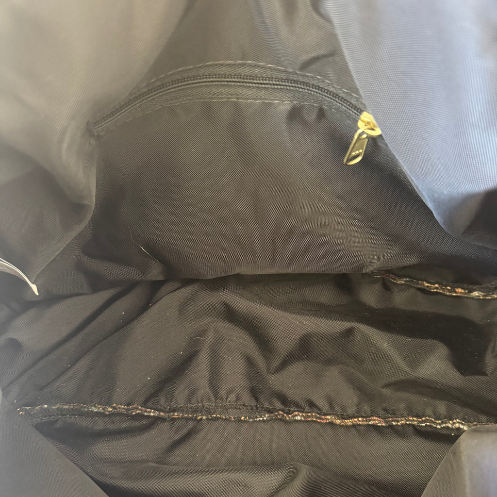 Close-up of the interior of a black jacket or bag, showing a zippered pocket with a gold zipper pull and stitched seam details.