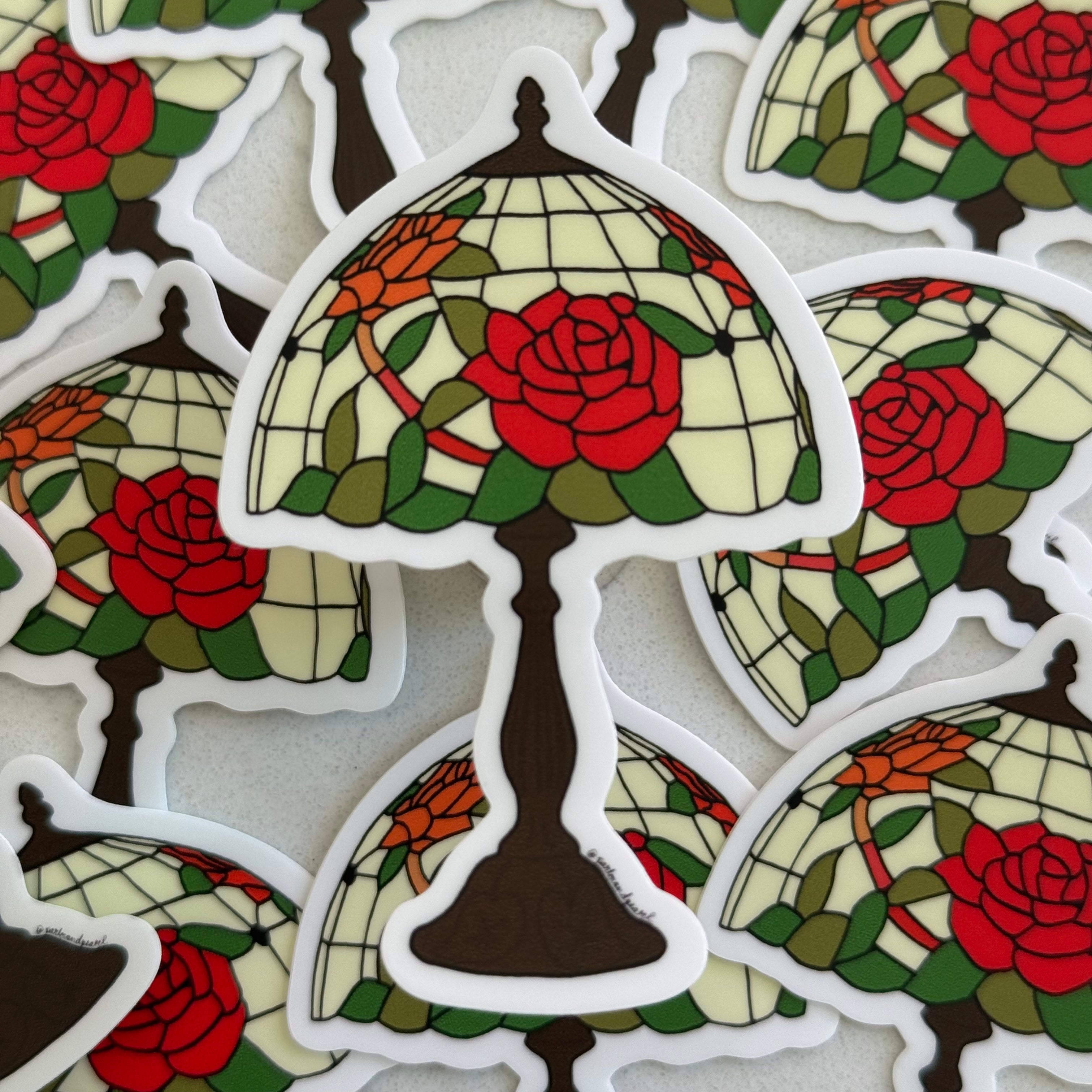 Die-cut vinyl sticker featuring an original illustration of a Tiffany-style lamp with a cream stained glass shade decorated with red roses and green leaves on a dark bronze base